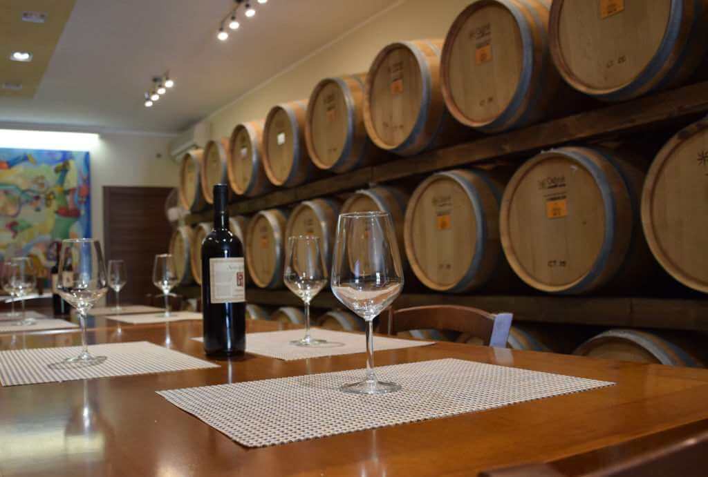 Wine tasting room with casks and a table with wine glasses and a bottle of red wine.