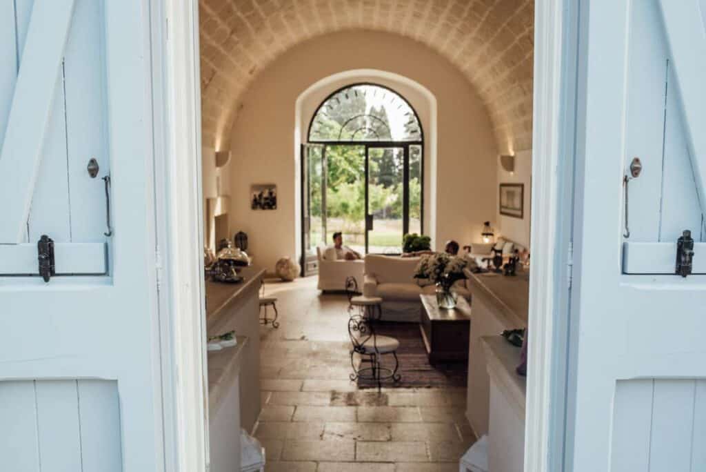 View through wooden barn doors into a stone arched room in a suite at Masseria Montelauro in Lecce Italy.