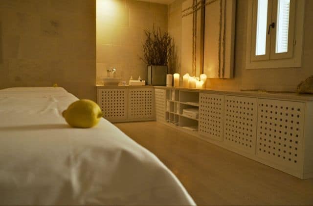 All white candle lit treatment room with lemon on bed at Vair Spa at Borgo Egnazia in Puglia Italy.
